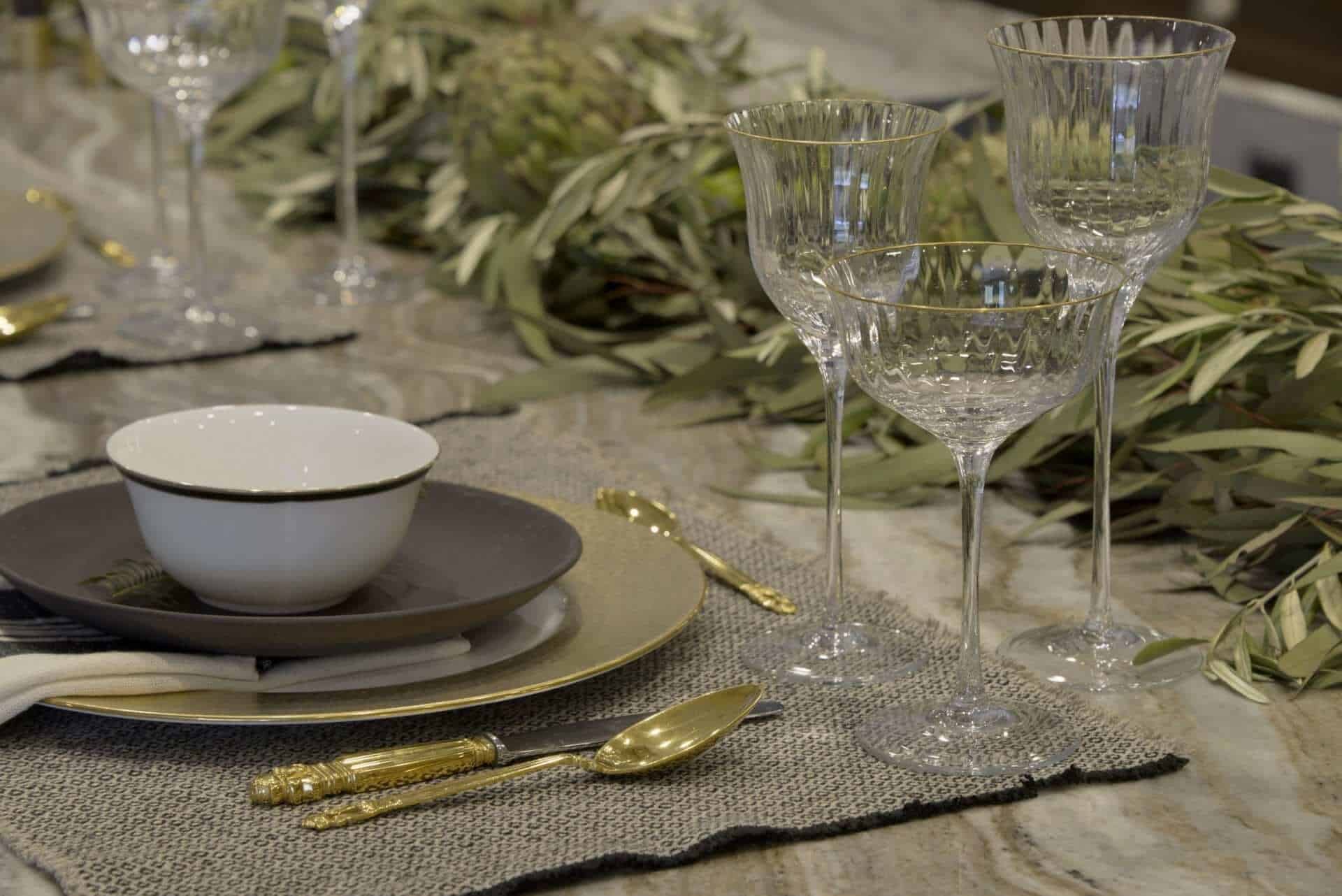 Tabelscape with gold flatware, textured placemat and fresh herbs