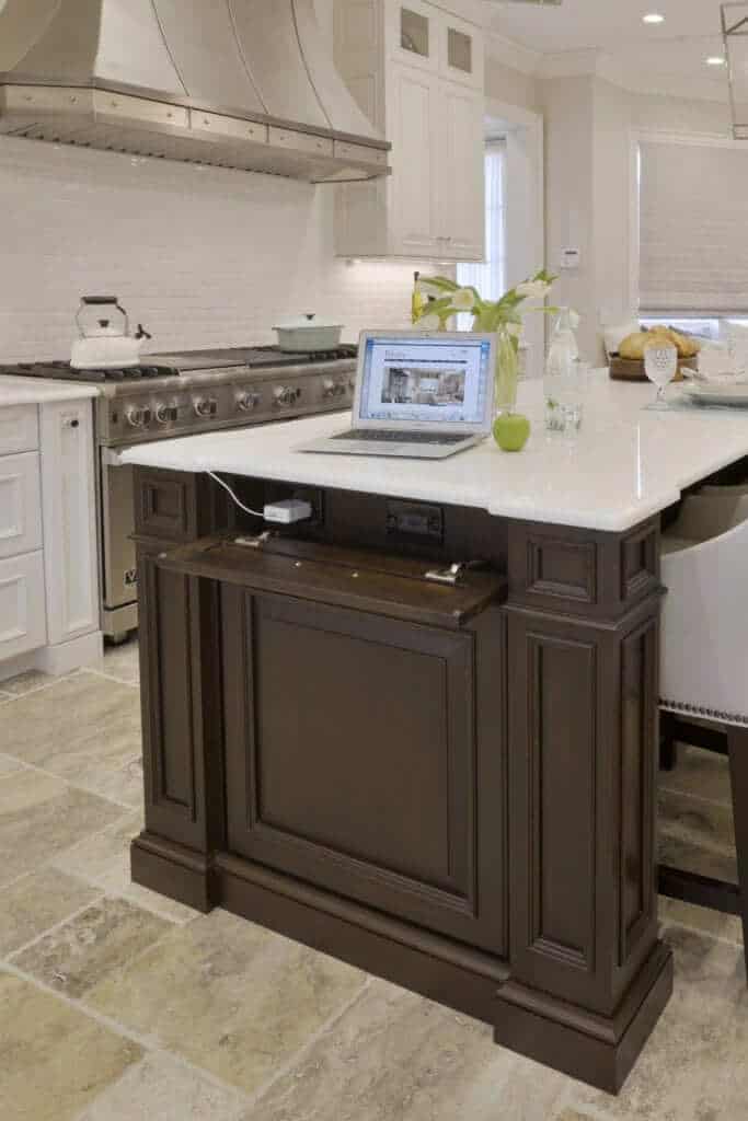 Classic white and cherry kitchen with hidden outlets and computer on island.