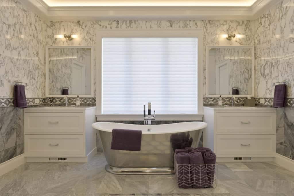 Luxury bathroom features custom white Bilotta cabinetry with polished nickel hardware and Calcutta and gray marble backsplash and flooring.
