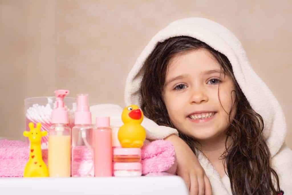 Little girl in towel with bathroom accessories.