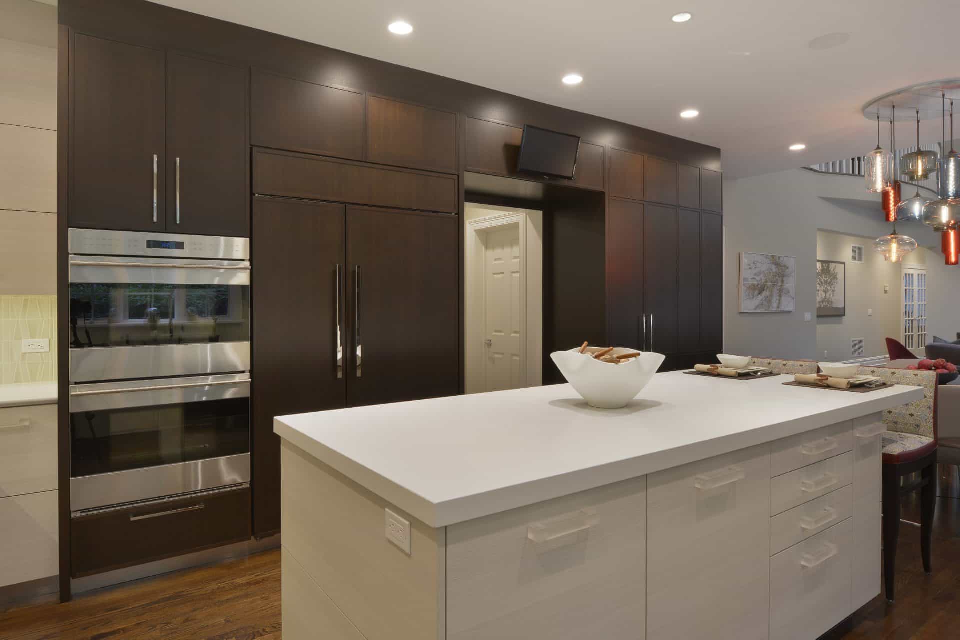 U-shaped kitchen features a mix of flat panel white textured laminate and shaker style walnut fully custom cabinets by Artcraft. The kitchen has white quartz countertops throughout, oak flooring, and a mix of chrome and red accents. Design by RitaLuisa Garces of Bilotta Kitchens.