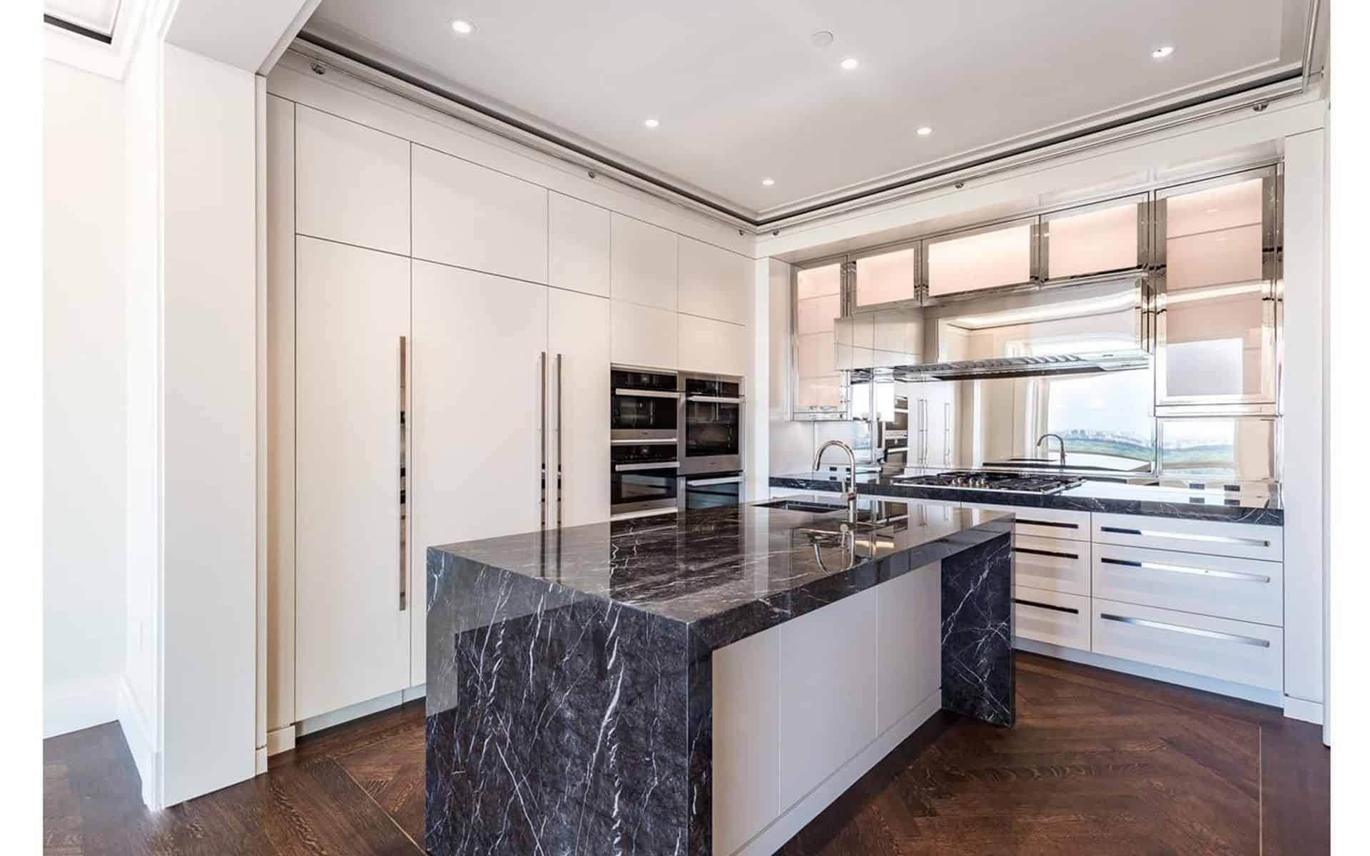 Custom kitchen with dramatic waterfall island, white custom cabinets and chrome accents.