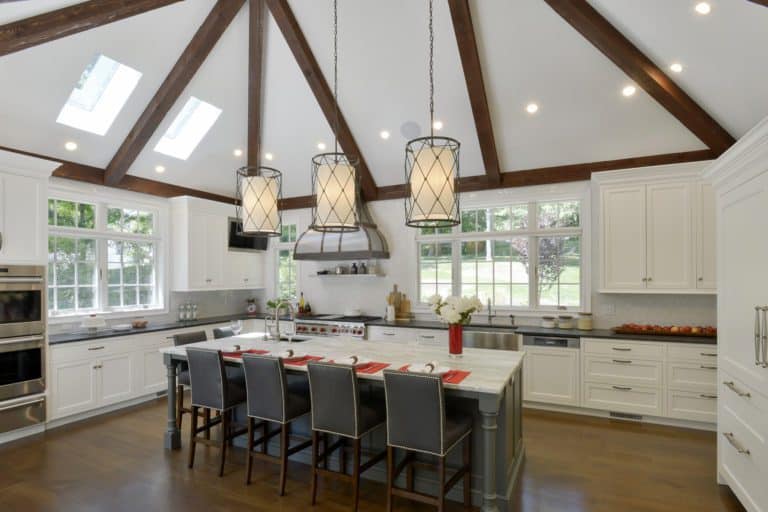 White classic kitchen features dark wood beams, custom marble-topped island, skylights and Bilotta cabinetry.