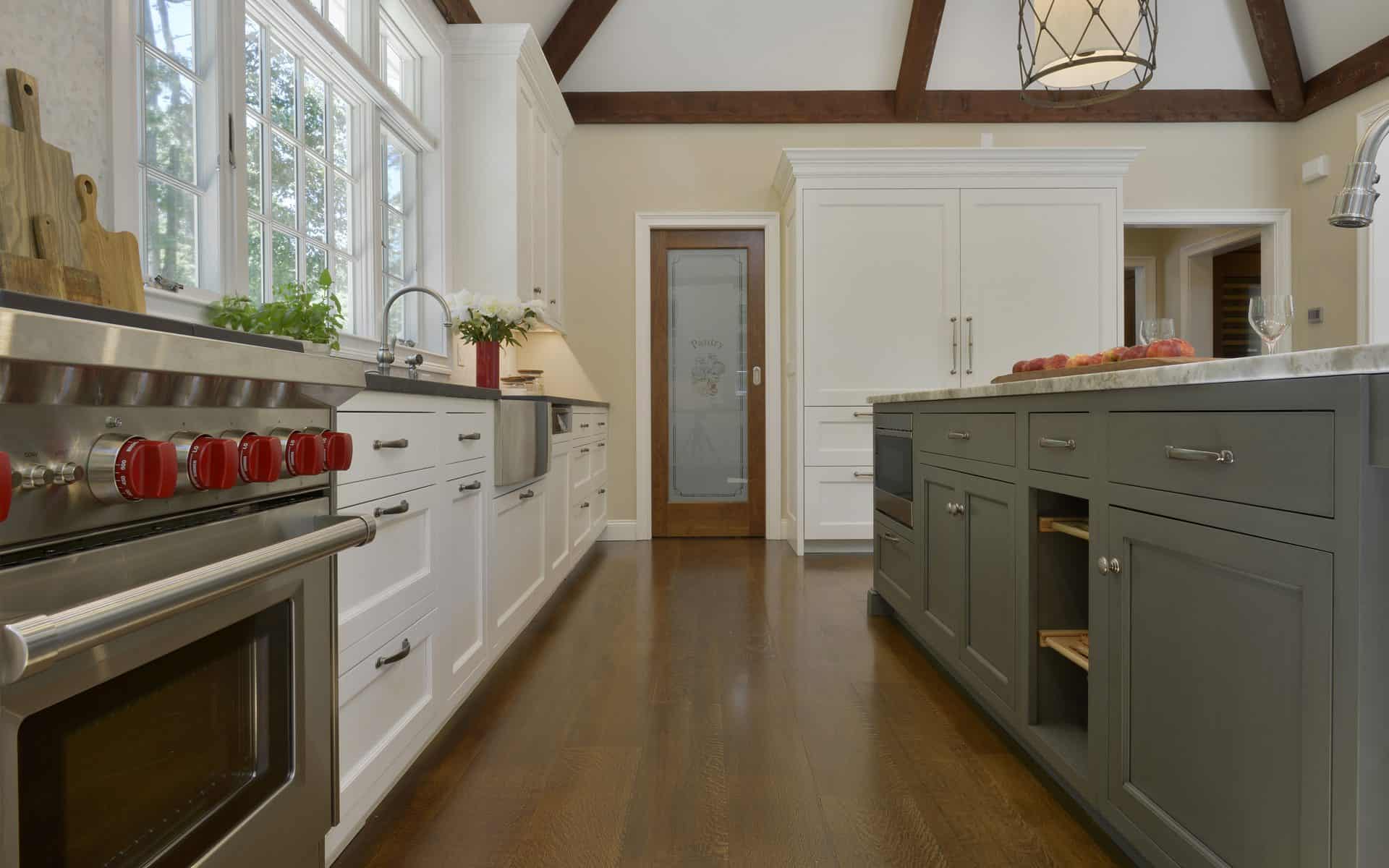 Kitchen features custom island with gray cabinets, dark wood floor and white custom Bilotta cabinetry.
