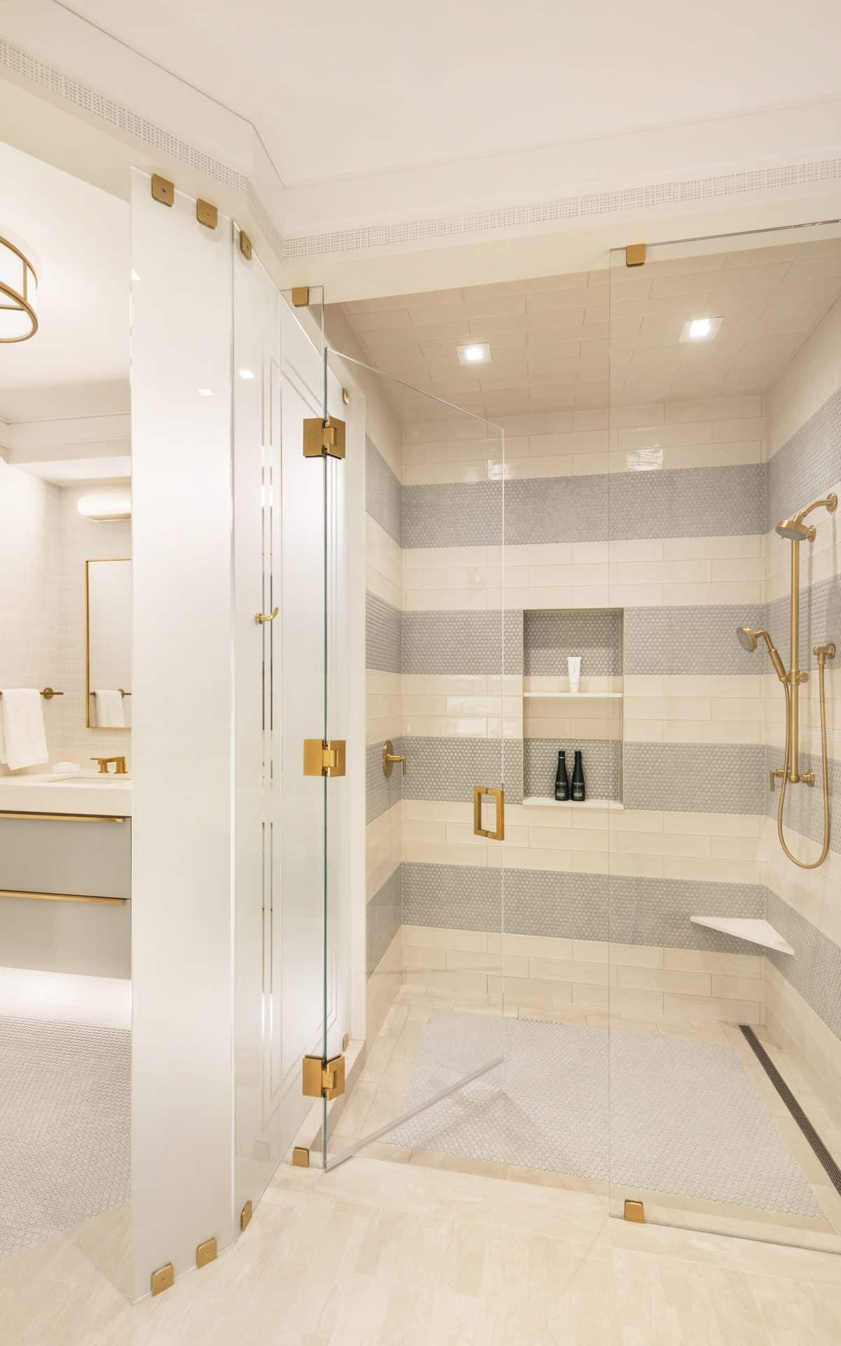 Luxury bathroom features modern design with high-end tiles, gold accents, and large shower with glass doors.