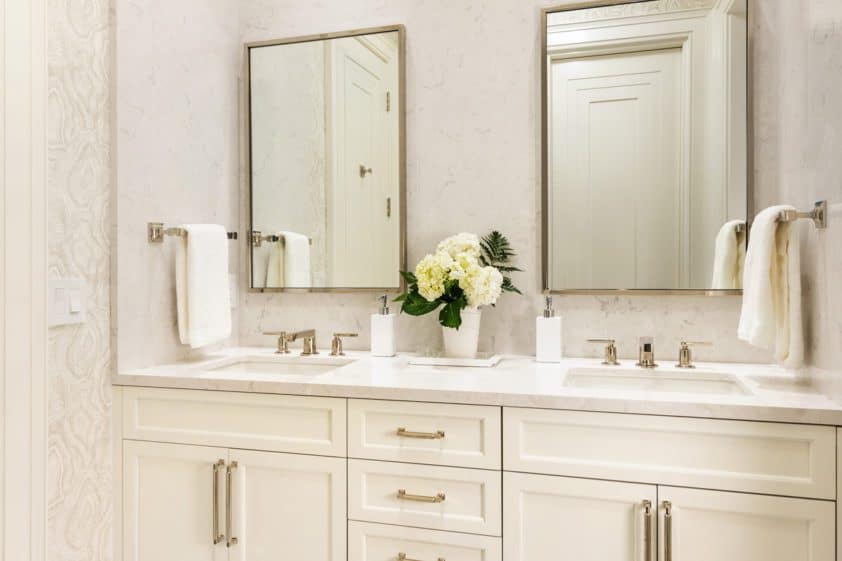 Elegant vanity features custom cream Bilotta cabinetry, double sinks and mirrors, classic gold accents and recessed lighting.