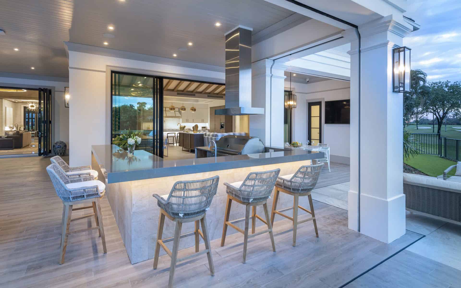 Stunning poolside patio features custom wrap-around bar with silver hoodvent and range.