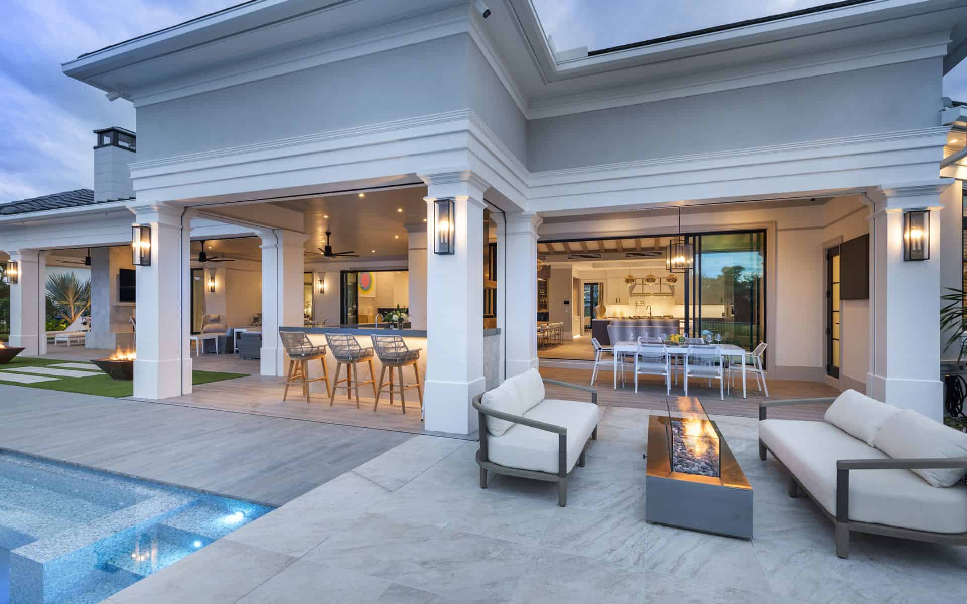 Stunning poolside patio features modern furniture and fire table, custom bar and custom eating area.