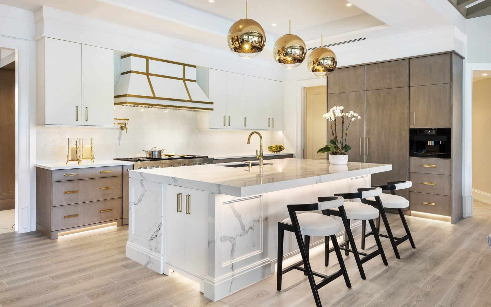 Stunning white classic kitchen features custom Bilotta cabinets and range, white and gray marble custom island and gold pendant lights.