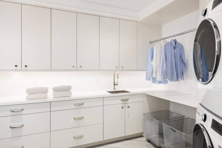 Custom laundry room features white Bilotta cabinetry, ample storage, and functional folding area.