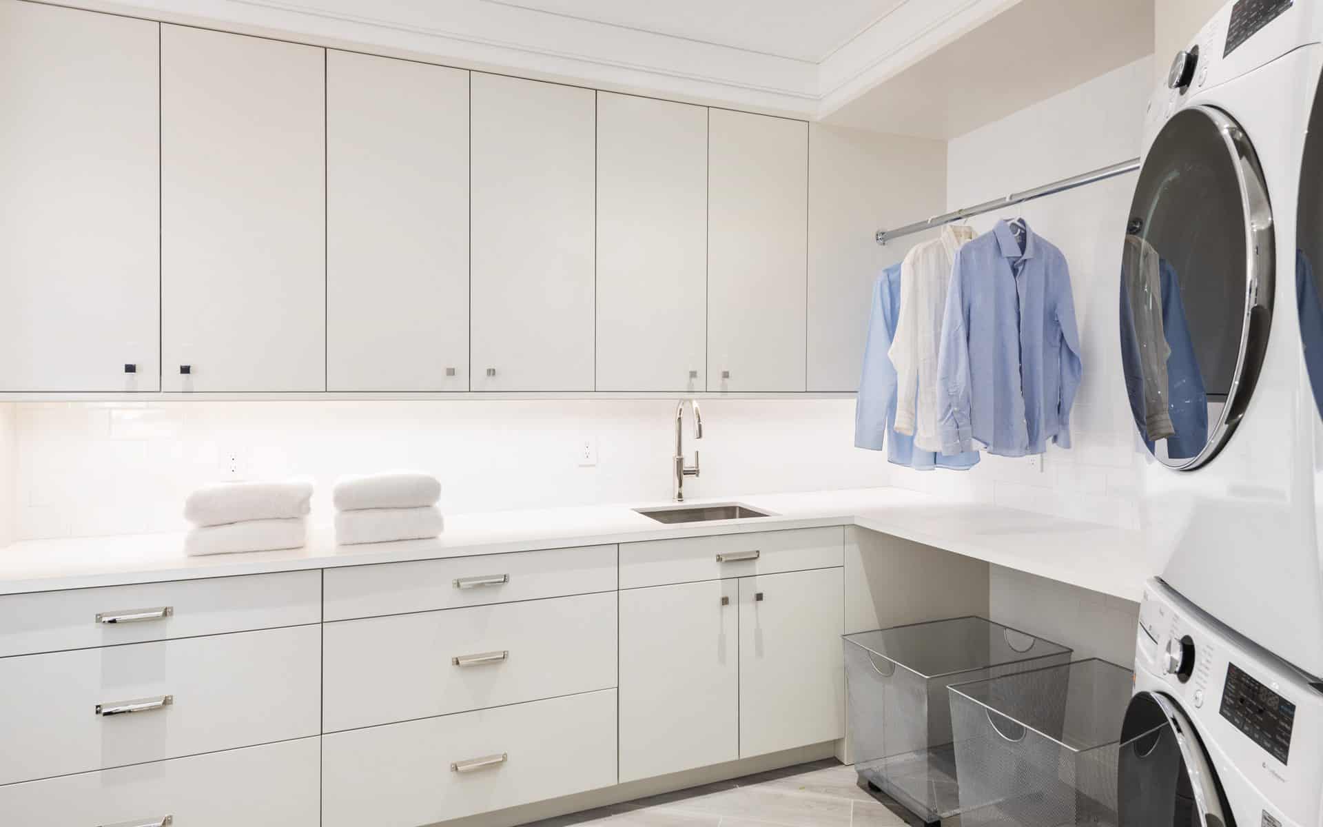 Custom laundry room features white Bilotta cabinetry, ample storage, and functional folding area.