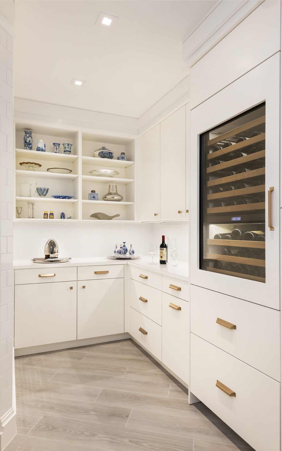 Kitchen features white Bilotta cabinets with gold drawer pulls and custom built-in wine storage and cooler.
