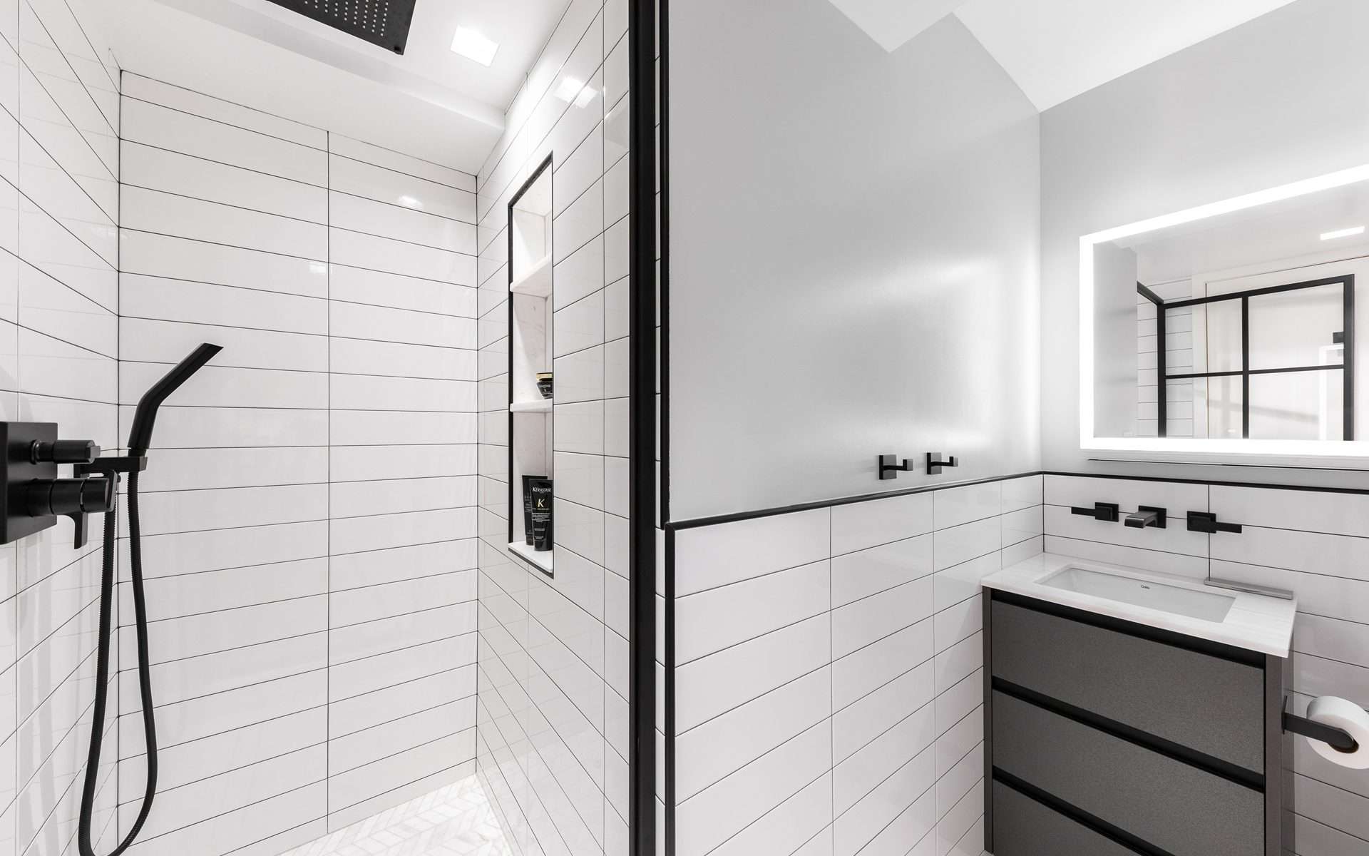 Statement-making bathroom features white subway tiles, black cabinetry and accents and modern appliances.