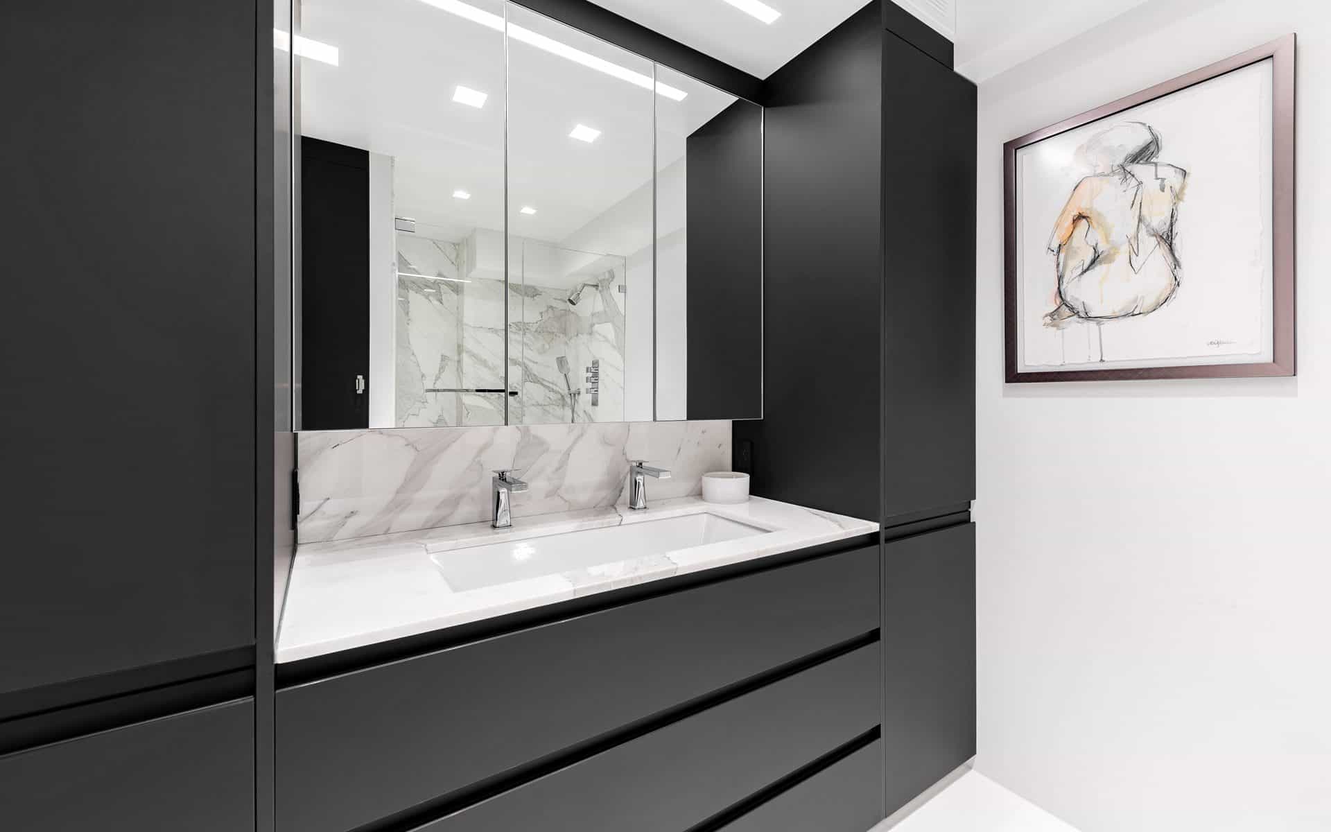 Modern custom bathroom features black Bilotta cabinetry with no handles, mirrored backdrop and modern accents.