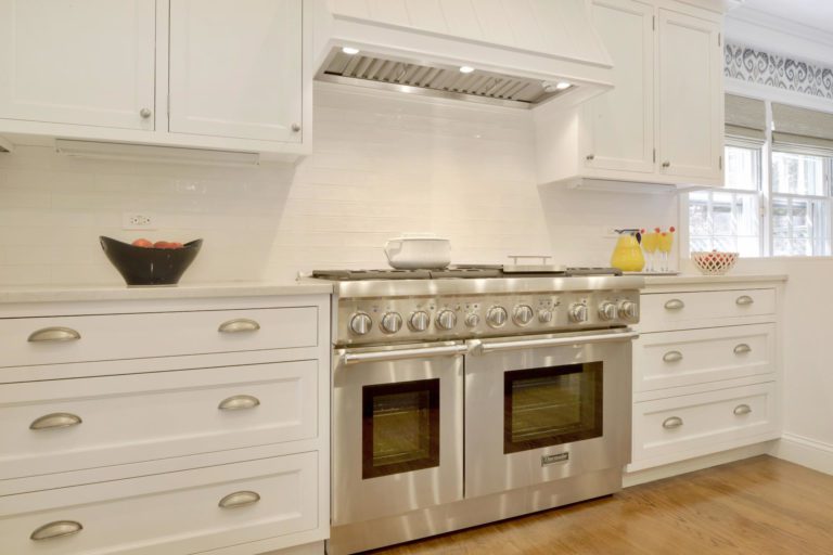 white kitchen with brushed nickel hardware and light wood flooring