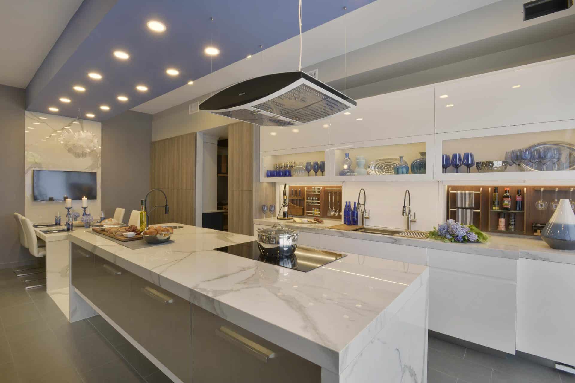 Custom kitchen features waterfall island with built-in cooktop and sink. 
