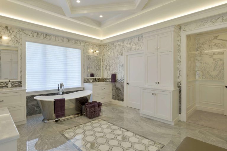expansive bathroom with tray ceiling, stainless steel bathroom, and marble walls