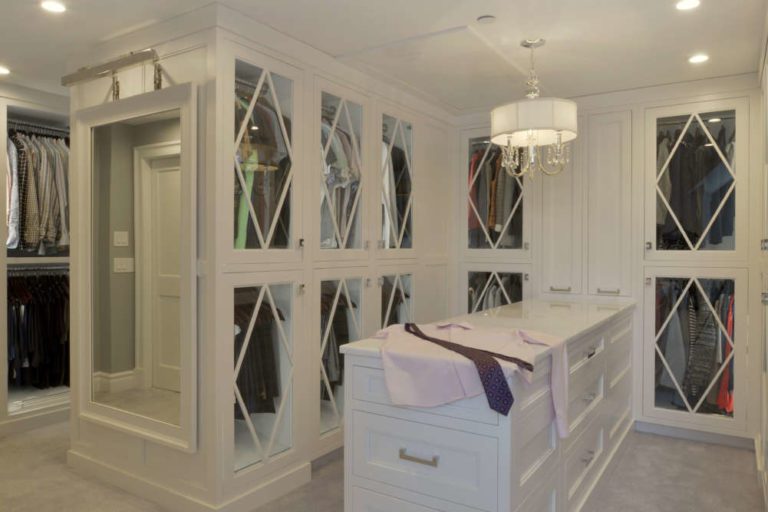 large walk-in closet with white cabinets and doors and a peninsula with drawers in the middle