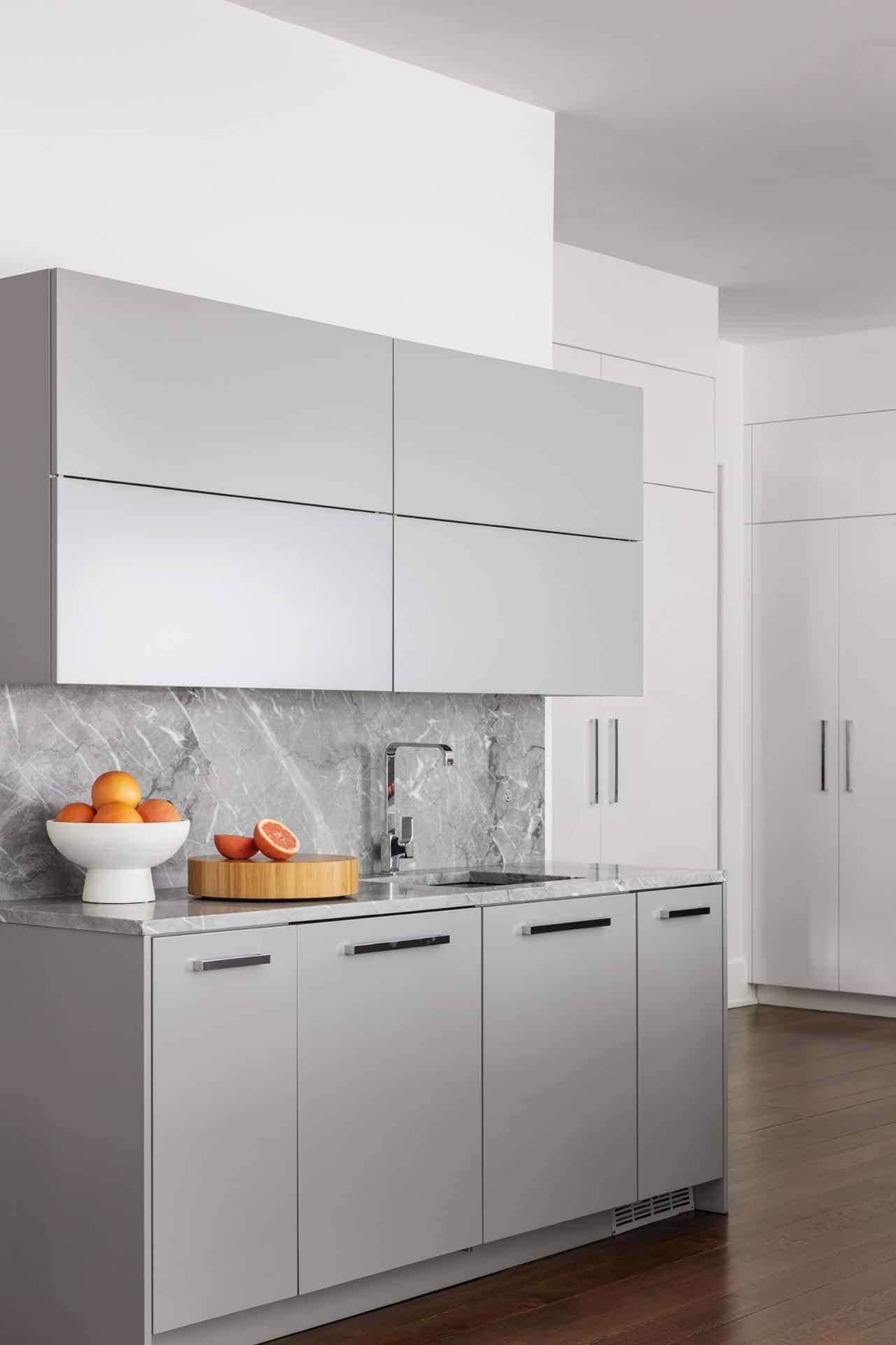Contemporary kitchen with gray and white flat-panel cabinets. The countertops and backsplash are gray marble.