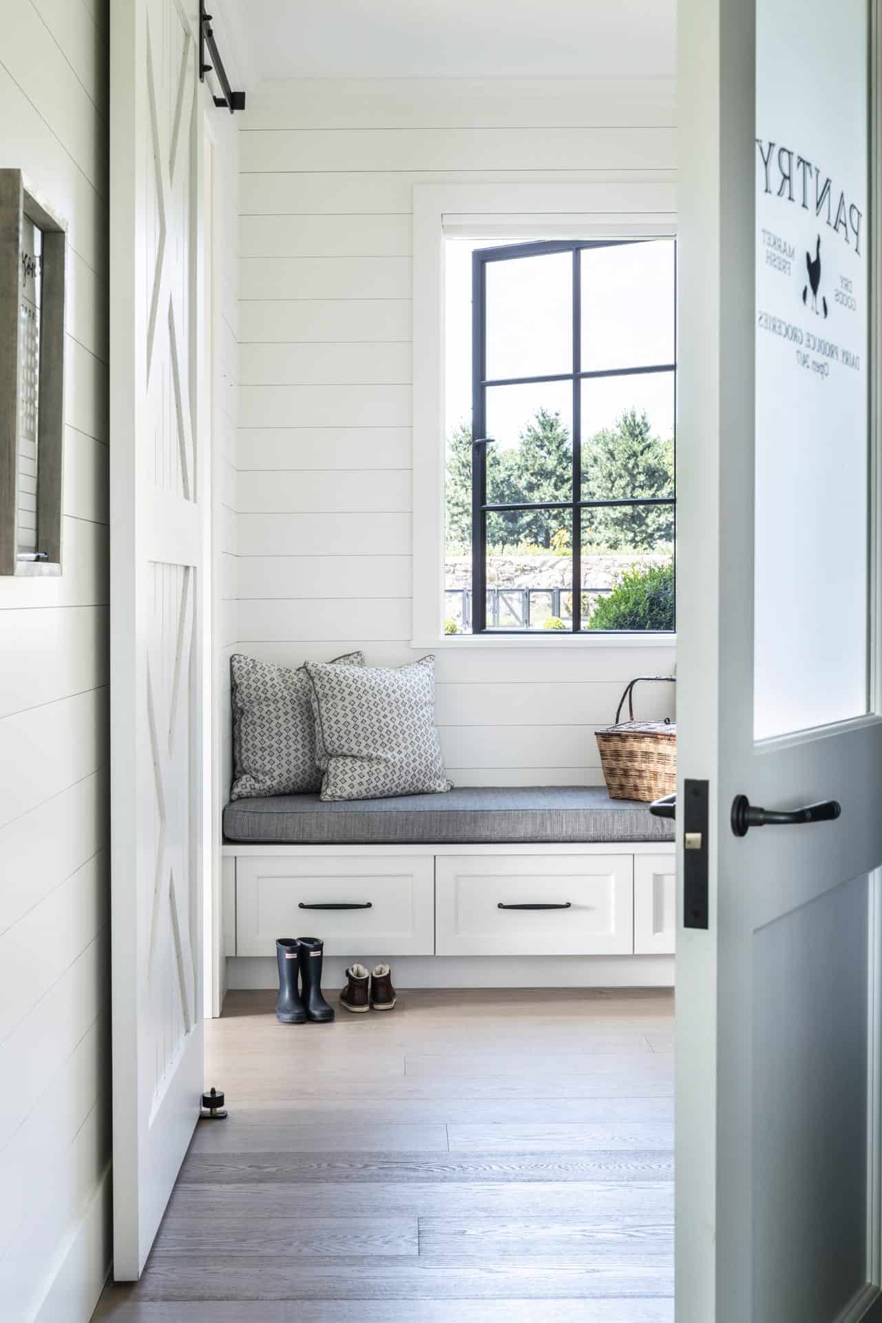 White and gray toned mudroom off the kitchen with a bench.