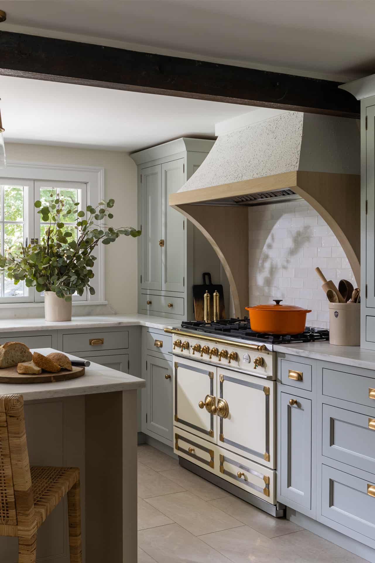Traditional kitchen with inset Bilotta cabinetry in a mix of Farrow & Ball light blue and natural cream. Counter tops are Danby marble with La Cornue range and oak accents.