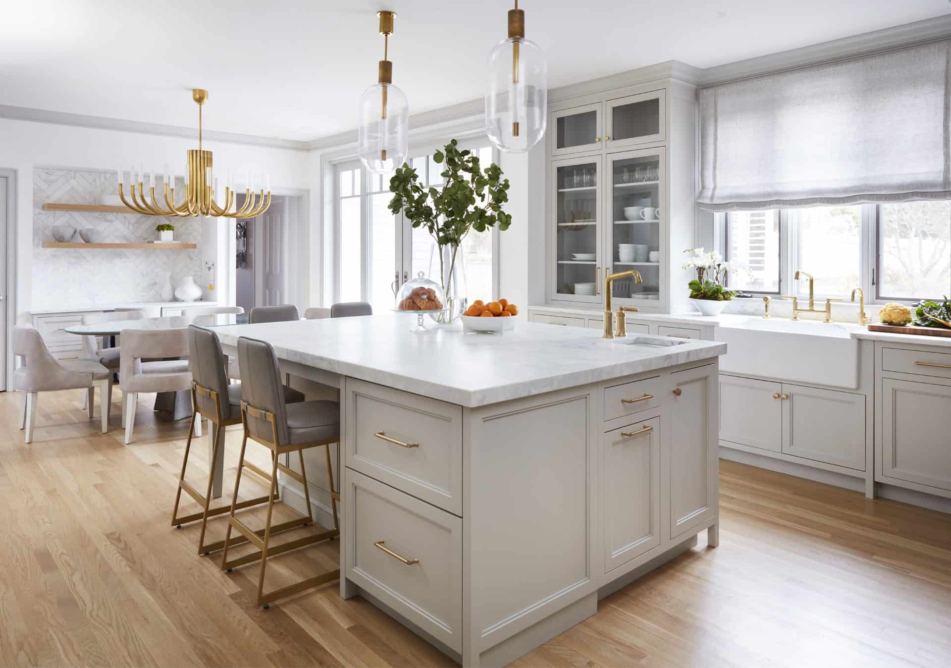 Kitchen and dining with Bilotta Collection cabinetry with brass hardware, with marble island and counter tops and herringbone marble backsplash