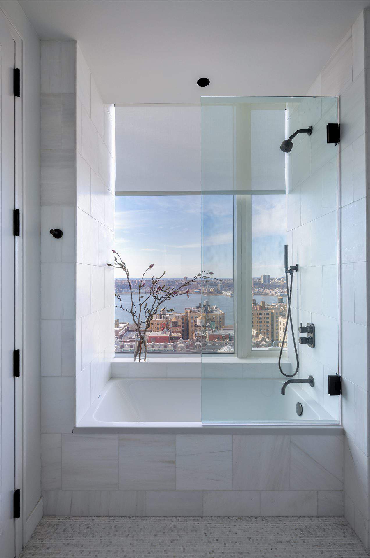 View of white tiled shower overlooking NYC skyline and Hudson River