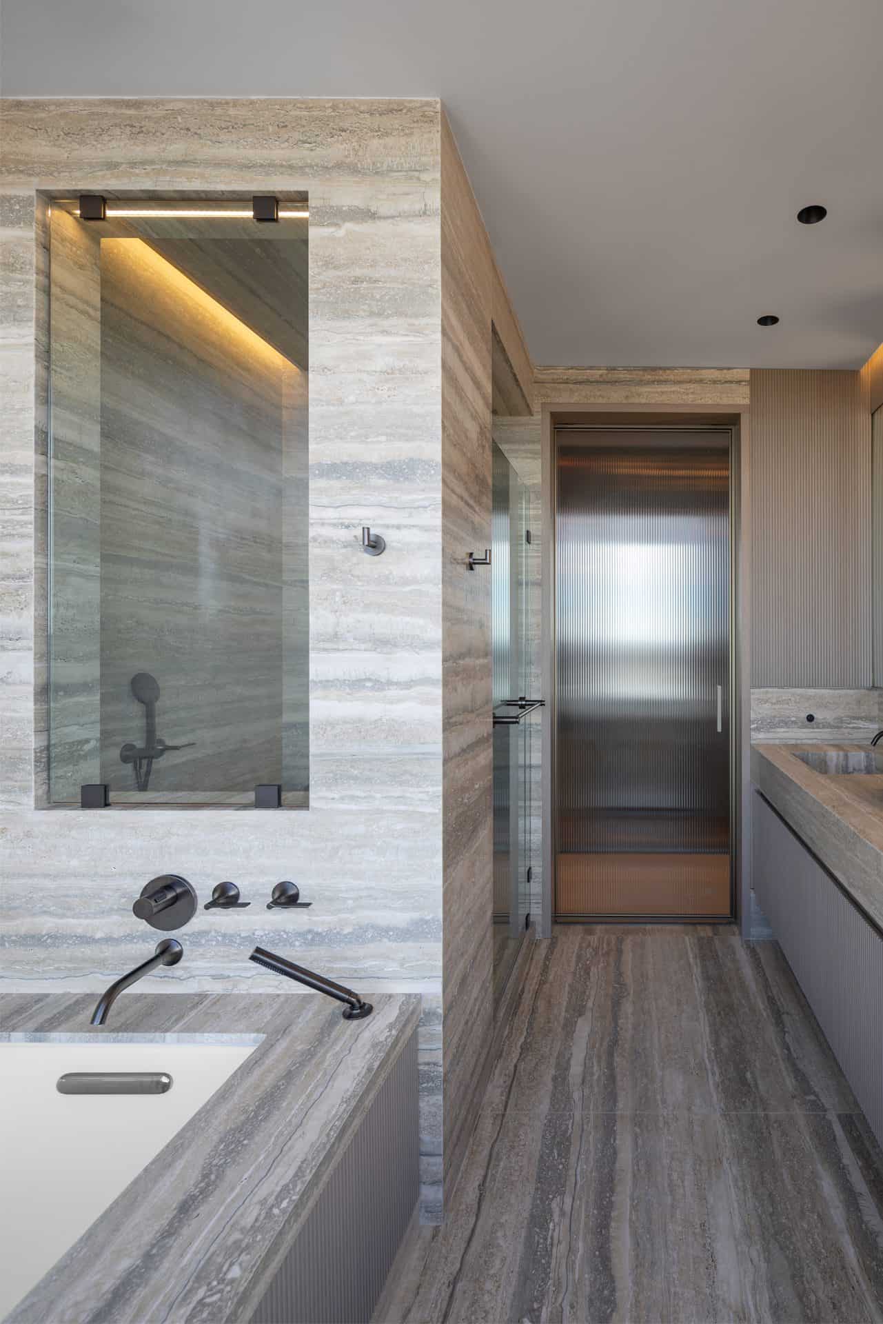 Earth-toned bathroom with Bilotta double sink vanity, pocket glass door, view of stand alone tub and enclosed shower.