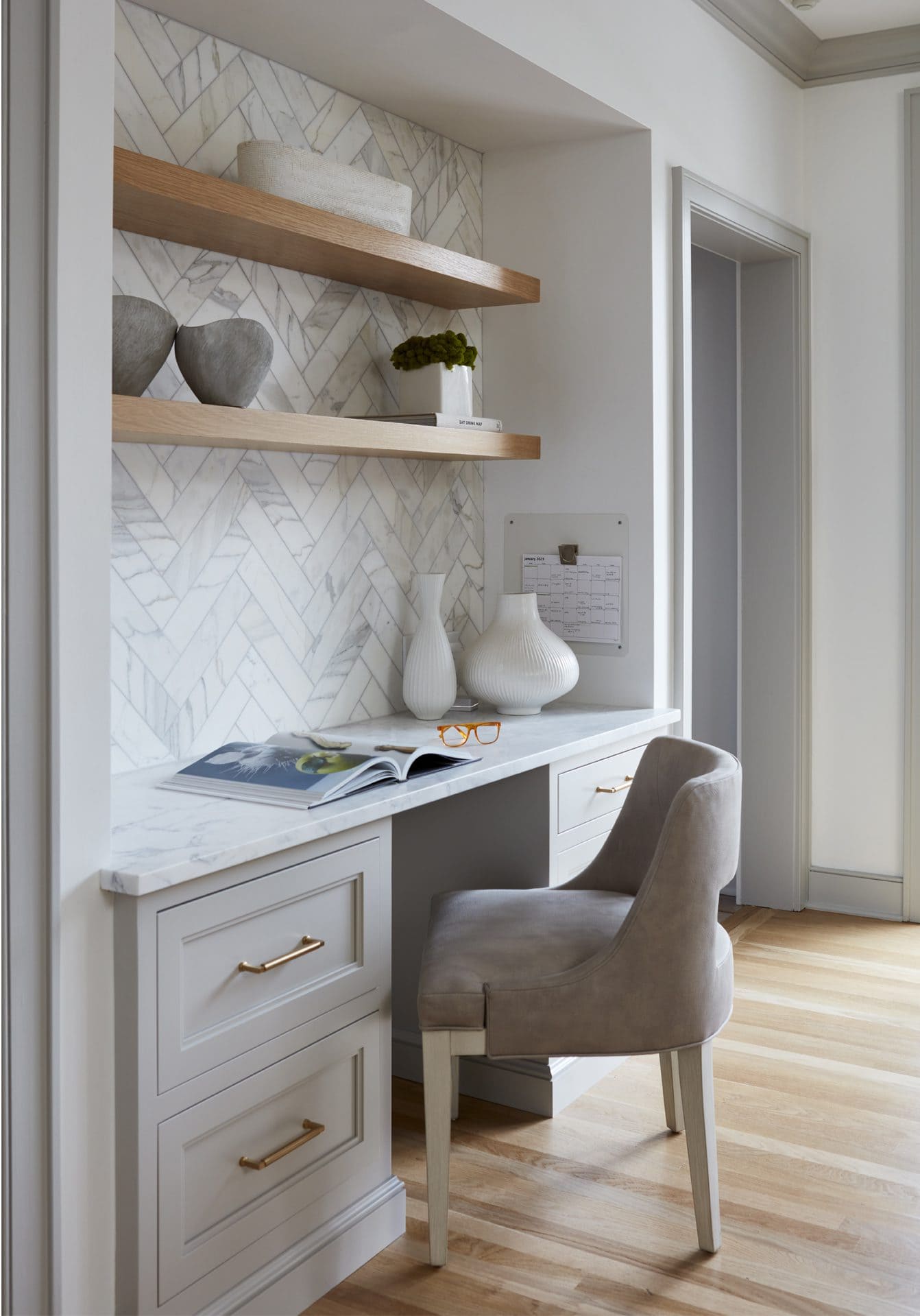 Built-in desk with floating shelves and herringbone marble tile backsplash