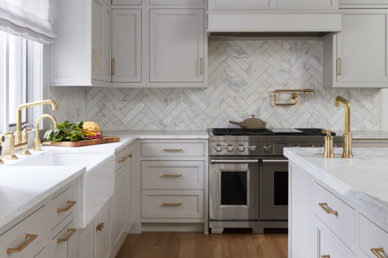 Classic kitchen with Bilotta Collection cabinetry with brass hardware, with marble island and counter tops and herringbone marble backsplash