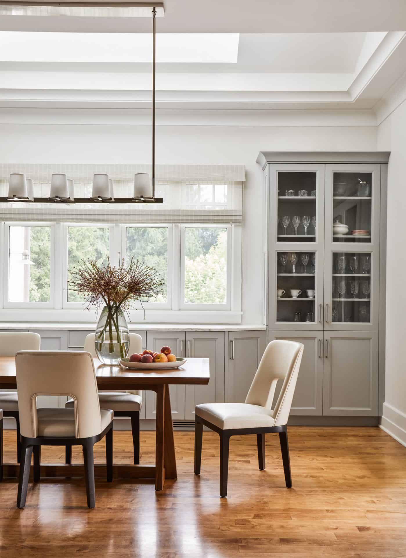 Dining room with built in gray base cabinets and glass front custom hutch