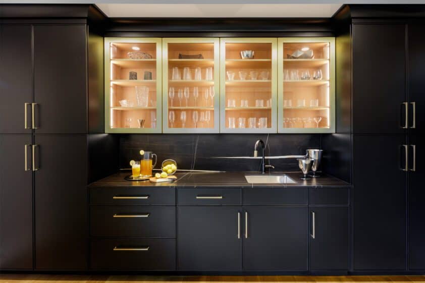 View of Bar with black base and talls cabinets and glass front upper cabinets