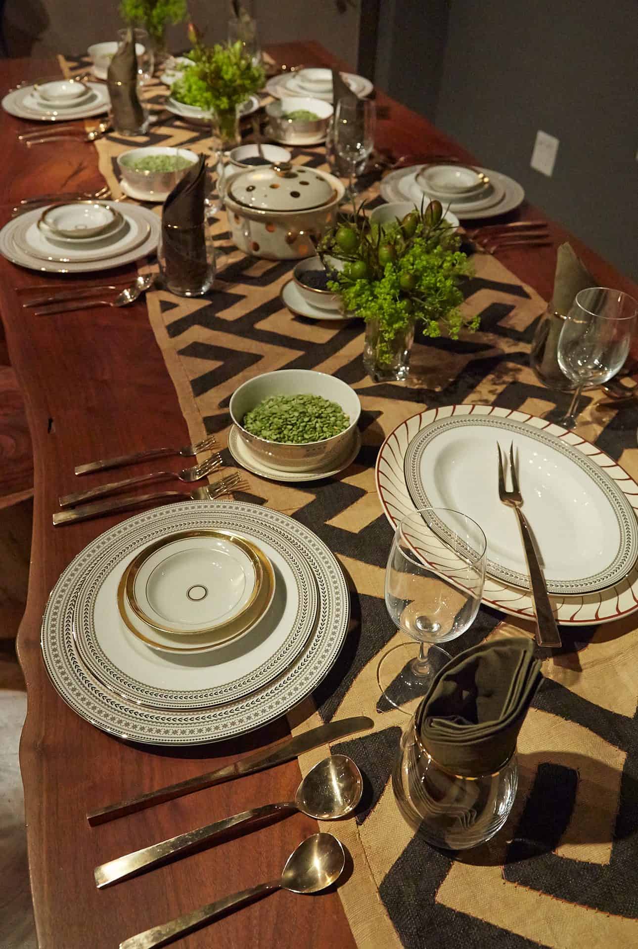 Tabletop design using a mix of black and gold plates and gold flatware on a live edge walnut dining table.