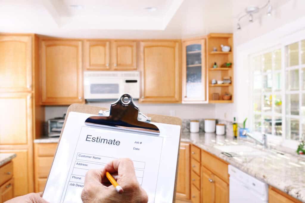 Clipboard with a hand writing an estimate inside a kitchen